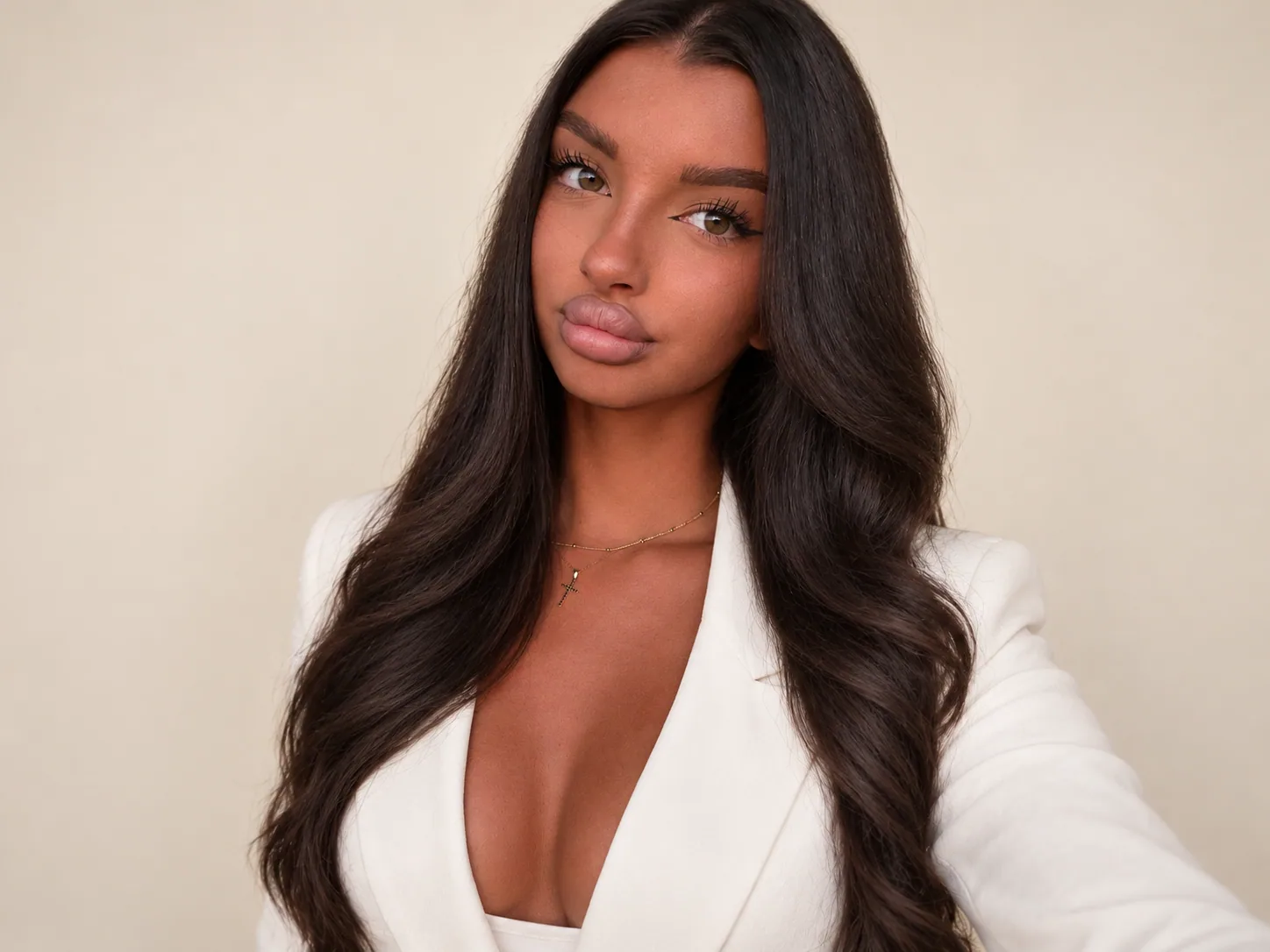 Alessia Cojocariu, cu părul lung, negru, ondulat, în sacou alb, pe fundal crem